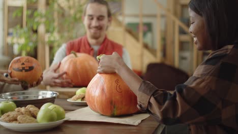 friends show to each other their ready painted pumpkins