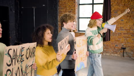 side view of young environmental activists with placards and megaphone walking and protesting against climate change inaction