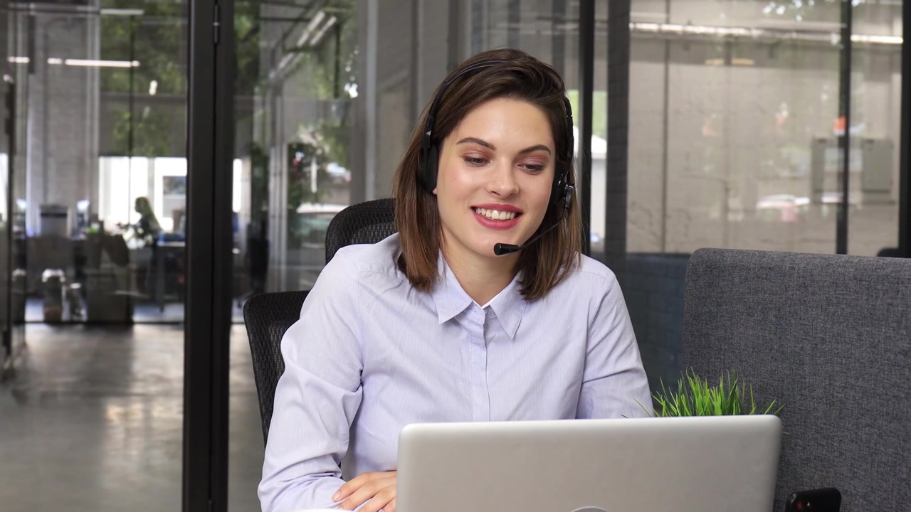 Mujer joven con auriculares hablando en videollamada en la oficina