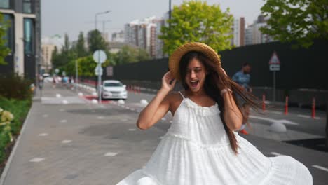 mujer con sombrero de paja y vestido blanco en la calle de la ciudad