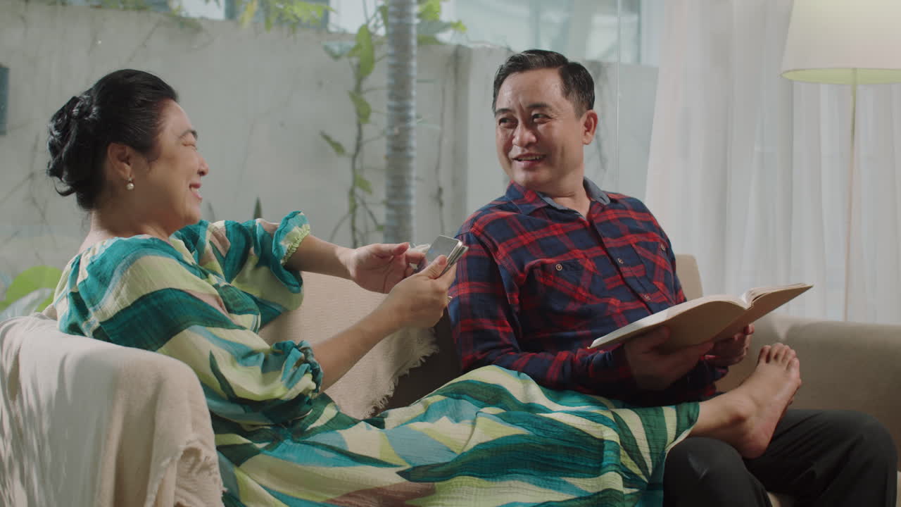Asian Husband Sitting next to Beloved Wife on Couch at Home