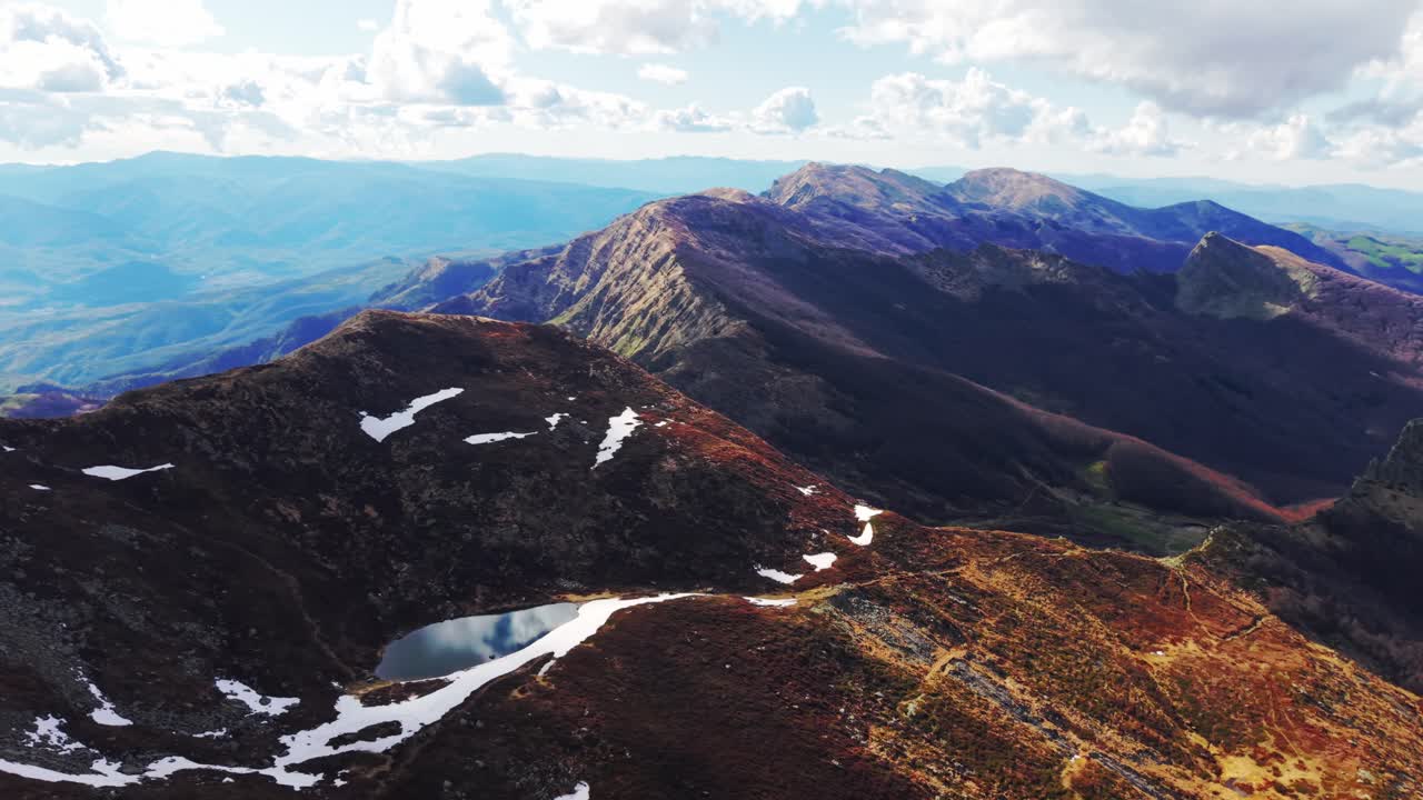 The dolomites mountains showcasing rugged terrain, snow patches, and expansive valleys, aerial view