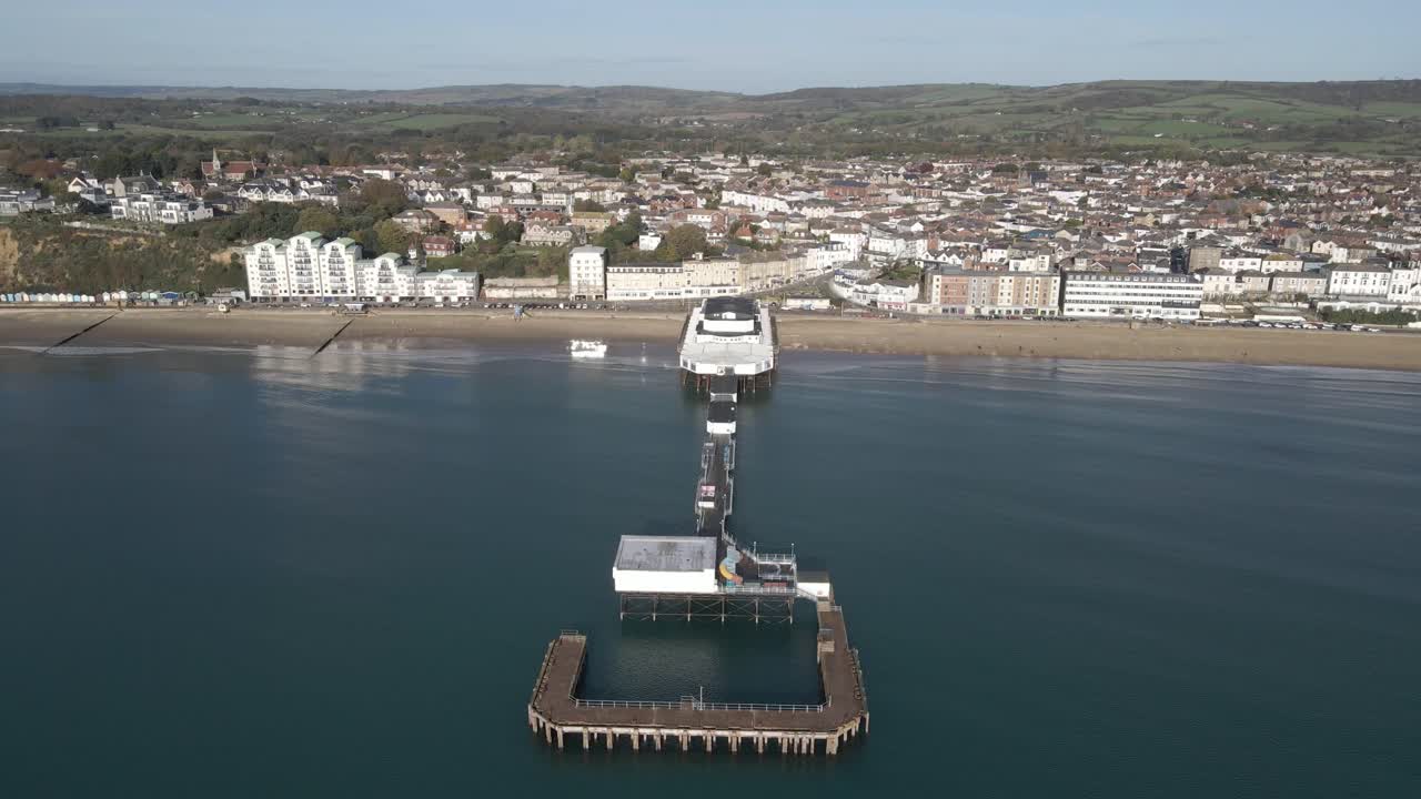 Aerial view of Sandown a seaside resort and civil parish on the south-east coast of the Isle of Wight, England. View of the Sandown pier with drone moving forward and camera tilting down