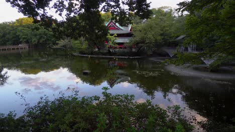 in kichijoji park, in tokyo, there is a beautiful sinto temple that is surrounded by intense nature and a large lake that reflects its figure