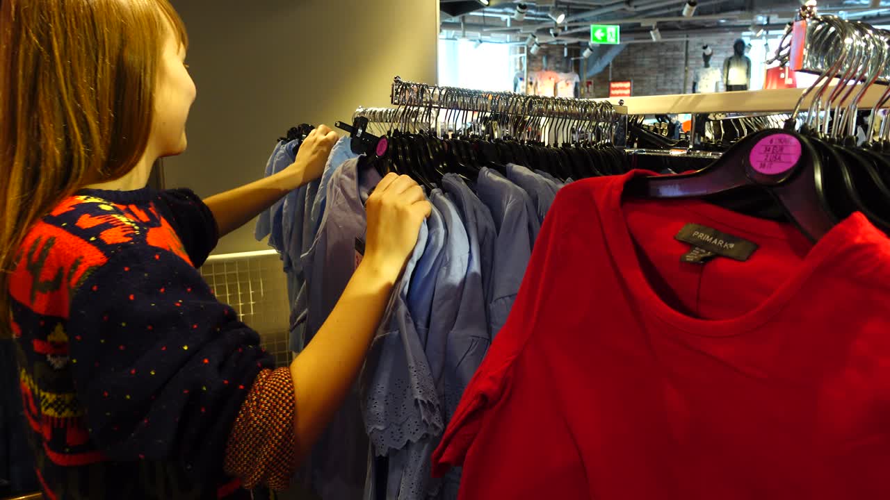 Compras en outlets de Europa. La chica elige ropa. Rebajas y descuentos