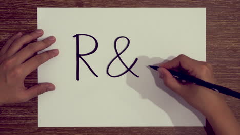 hand writing the word r-d on paper using brush pen marker