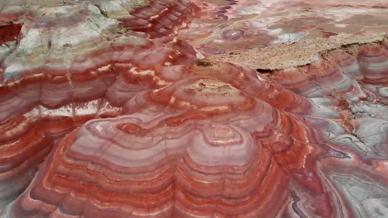 Imagens panorâmicas de drone capturam os tons vibrantes e marcianos das Colinas de Bentonita em Utah. O vídeo aéreo exibe formações dramáticas listradas em vermelho e cinza com detalhes cativantes.