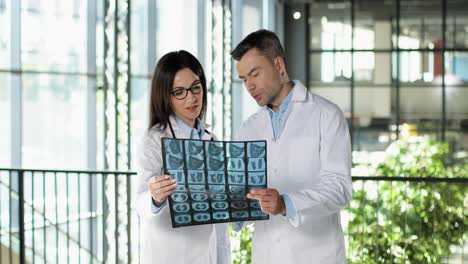 caucasian couple of male and female doctors standing in hospital, talking and looking at x-ray