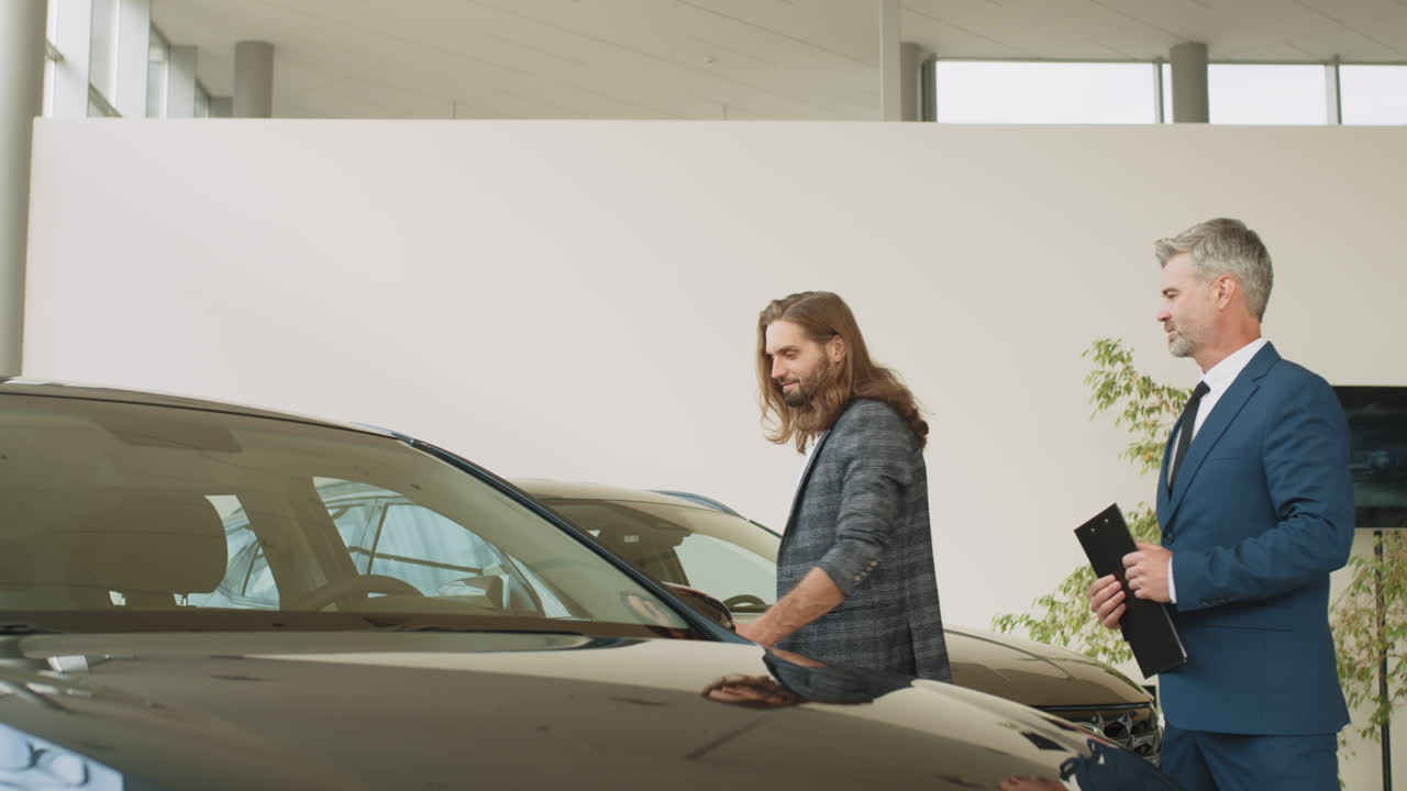 vendedor de coches mostrando coches a un cliente en una sala de exposiciones
