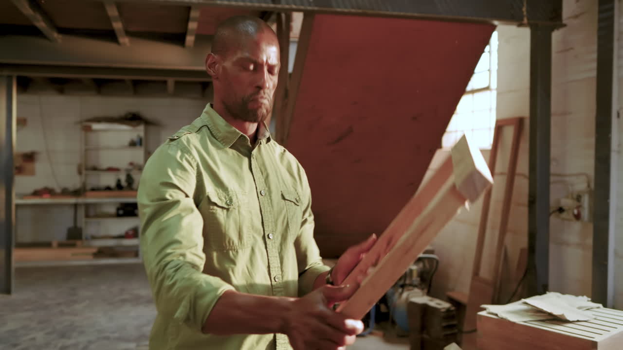 African American man firing nail gun into cabinet testing frame consulting tablet plans in workshop