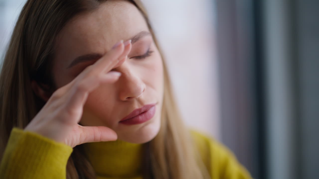 Frustrated woman suffering headache in modern office closeup. Stressed employee
