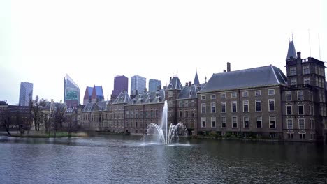 view of the binnenhof house of parliament and the hofvijver lake with skyscrapers in the background