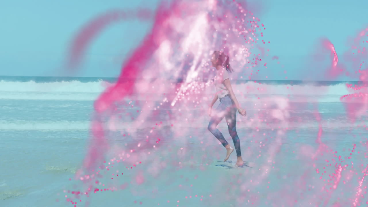 woman running along beach shoreline, with pink powder swirling, for creative marketing concept