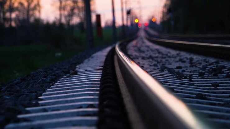 Dreamy low angle view of railroad tracks disappearing in the distance at sunset