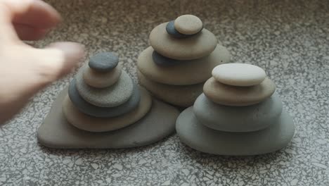 female hands stacking pebbles on windowsill in apartment, close up