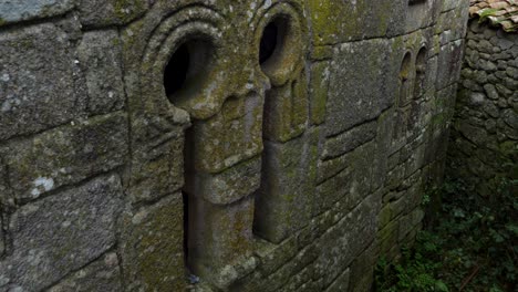 ornate carved archaeological remnant on side of church in spain, mossy rock