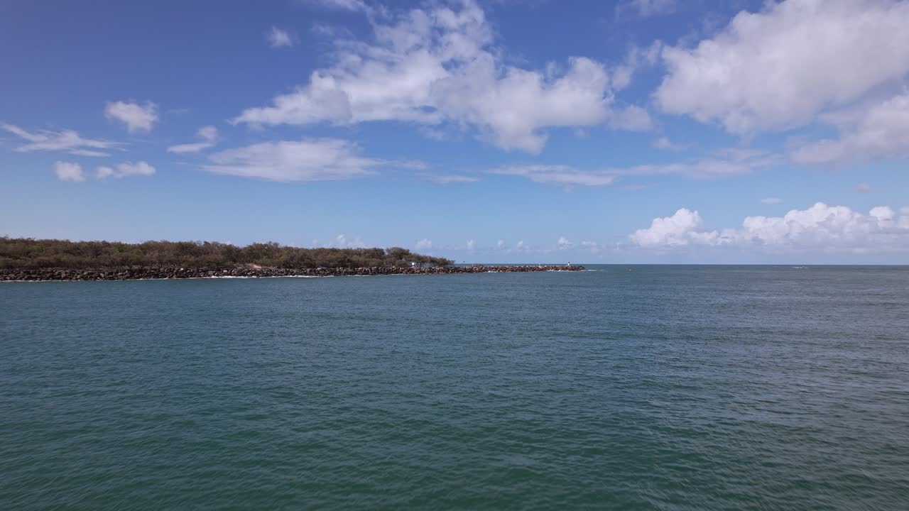 Low Flight Above Calm Waters Towards Seawall And Lighthouse On South Stradbroke Island In Queensland, Australia. ascending drone shot