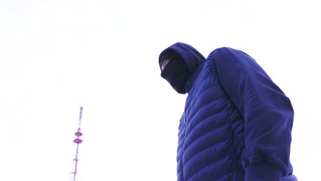 hombre con una máscara y chaqueta cerca de una torre