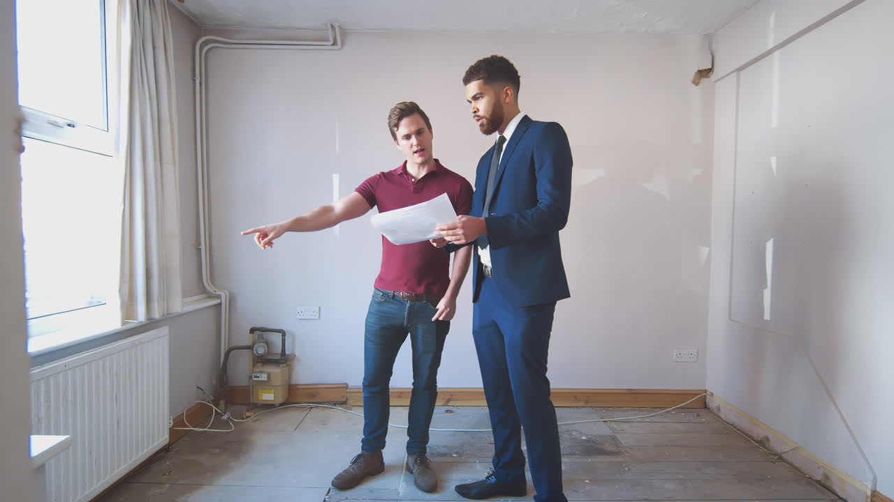 Homme primo-accédant examinant un rapport d'expertise immobilière avec un agent immobilier