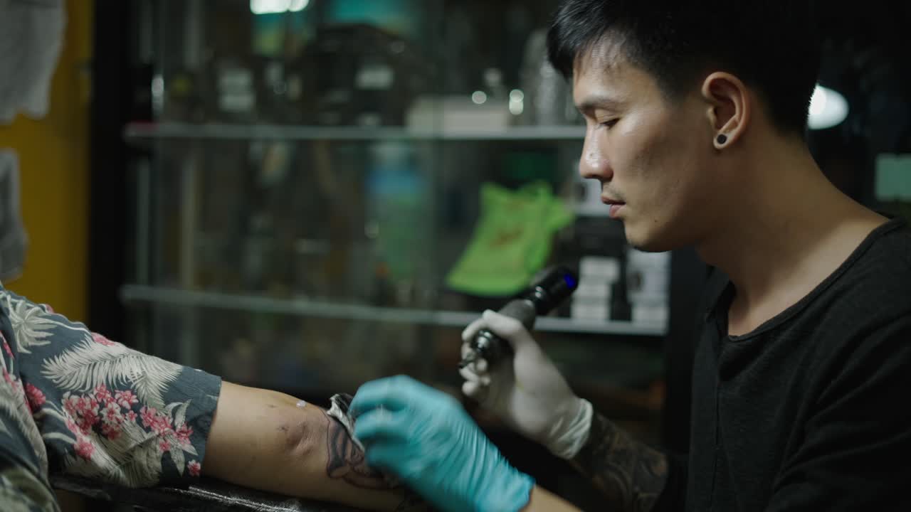 A tattoo artist working on a client's arm