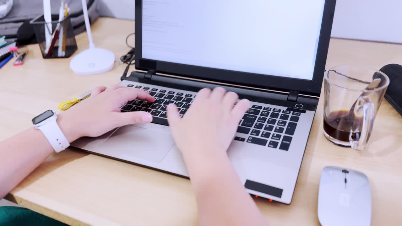 Front view of hands actively using a laptop, typing on the keyboard.