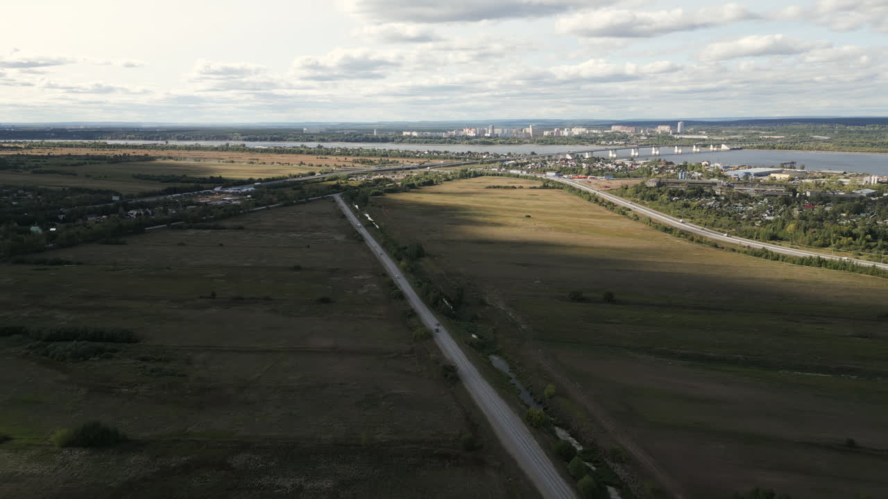 Aerial view of a countryside road and highway crossing near a river and city