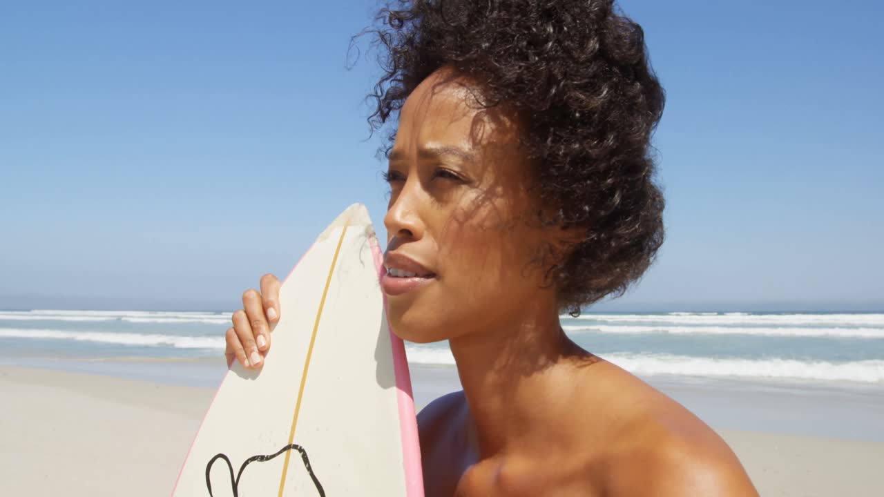 surfista de pie con una tabla de surf en la playa 4k