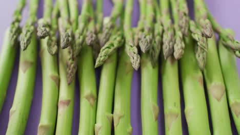 video of close up of fresh asparagus over lilac background