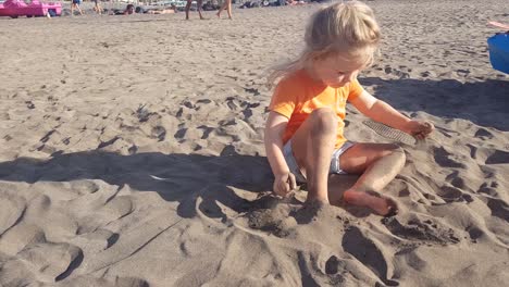child sitting throwing sand from the beach on top of it