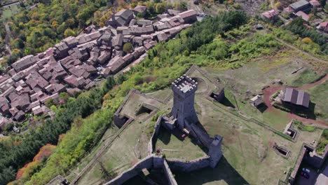 Above-Radicofani-fortress-with-defensive-layout,-overlooking-small-village-in-Italy,-sunny-day