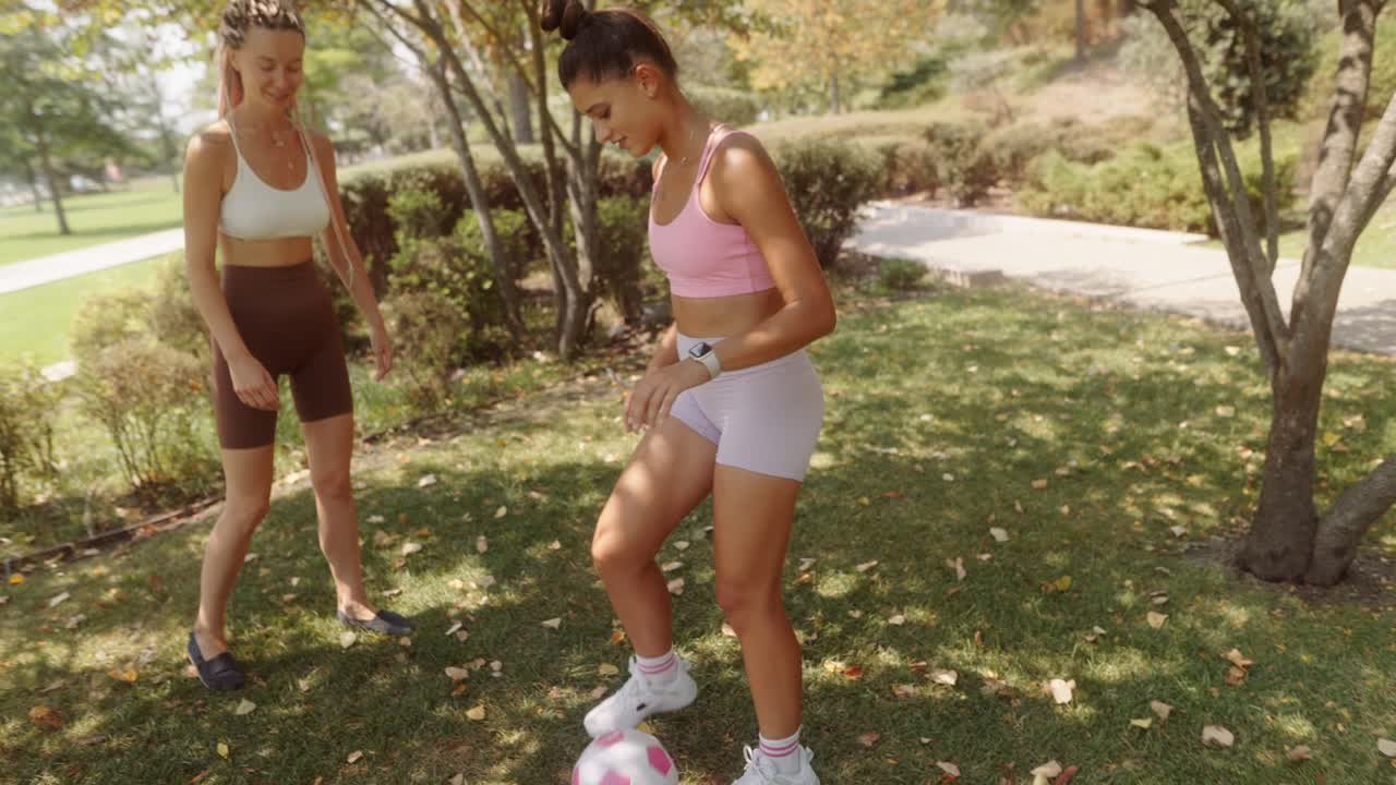 Two women playing soccer in a park