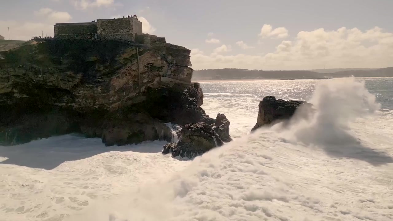 Ripresa in slow motion con carrello di un'onda che si infrange sotto il Forte de São Miguel Arcanjo