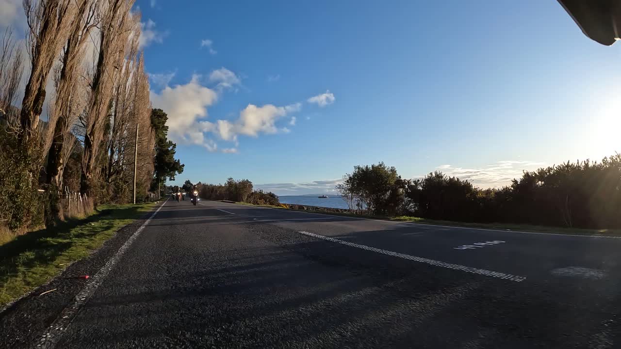 Group of motorcyclists on adventure motorcycles riding on a rural asphalt road at sunset. Northern Chilean Patagonia