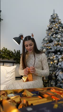 girl opening christmas gifts by the christmas tree