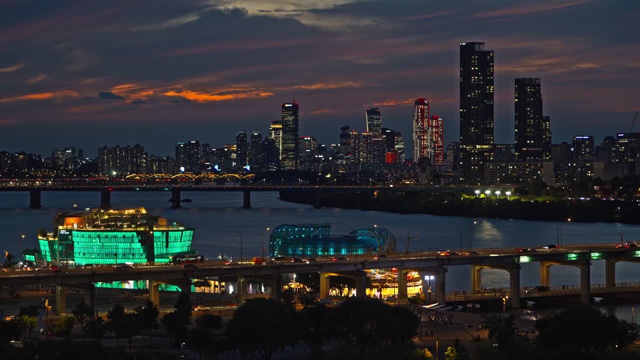 Real-time shot of the Seoul cityscape at sunset, featuring the glowing green Sebitseom floating islands on the Han River and the bustling traffic on the iconic Banpo Bridge