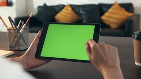 mujer sosteniendo una tableta digital con pantalla verde y dispositivo táctil navegando por internet.