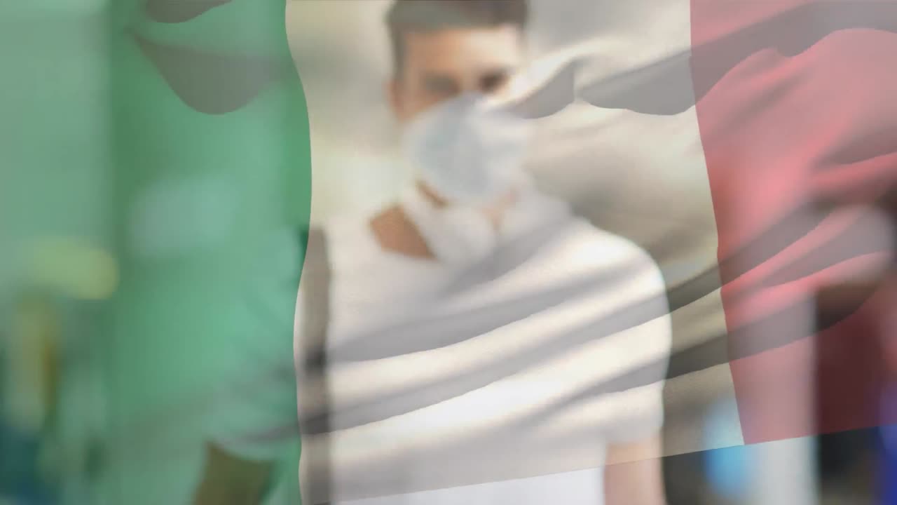 Animation of flag of italy waving over man wearing face mask during covid 19 pandemic