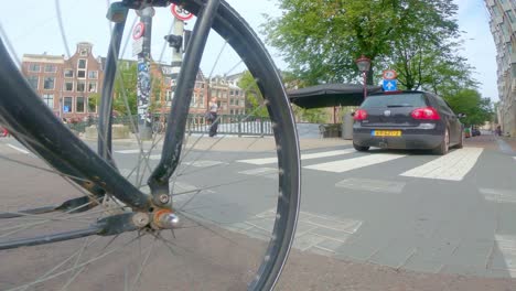 pov shot from the wheel of bicycle cycling through amsterdam city in the netherlands.