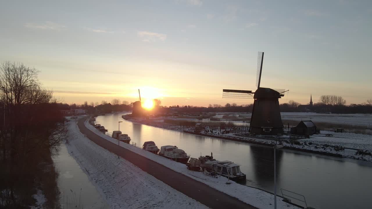 Vista aerea di un mulino a vento sul fiume Hoornsevaart in inverno all'alba ad Alkmaar, Paesi Bassi, con una splendida illuminazione all'alba, atmosfera calma, riprese drone di alta qualità che evidenziano la bellezza naturale
