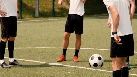 a young soccer man training freestyle tricks on a street football pitch while his team watching him 2