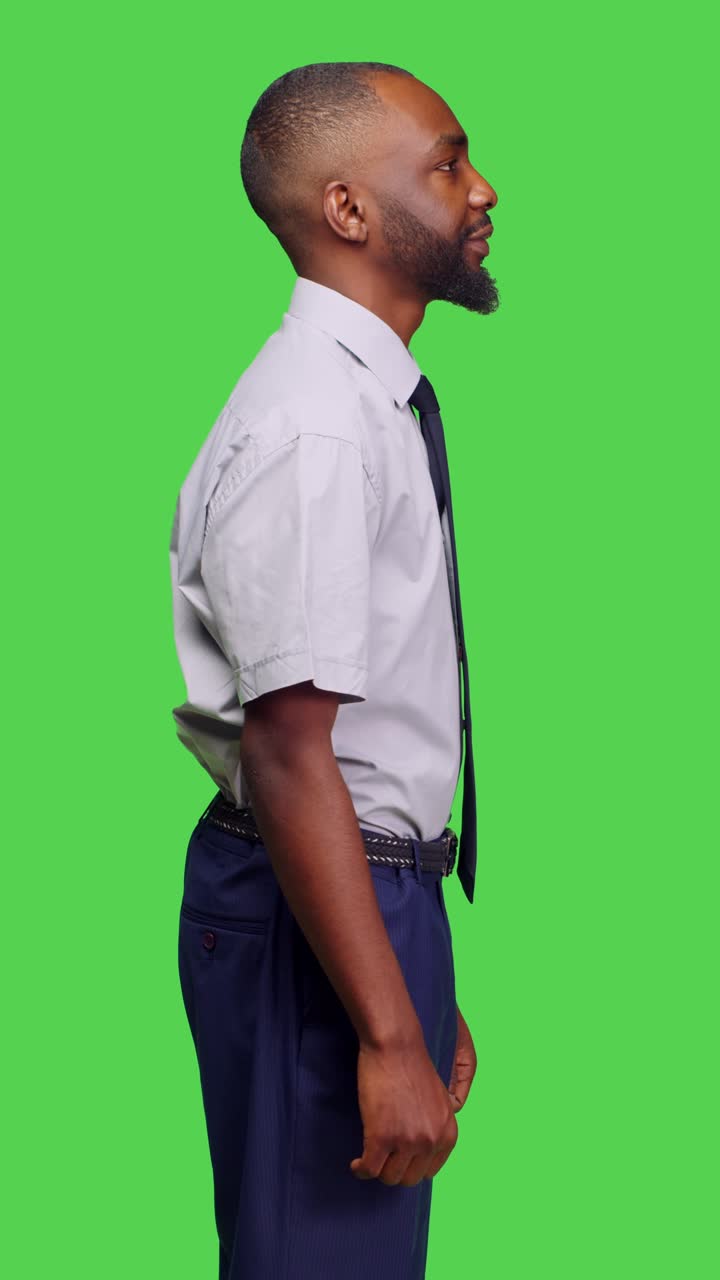 Vertical video: Side view of african american man standing over greenscreen backdrop