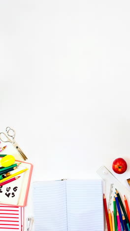 overhead shot of a hand writing in a notebook surrounded by school supplies