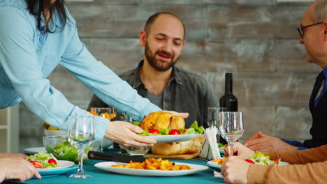 Young-wife-putting-tasty-chicken-on-the-table