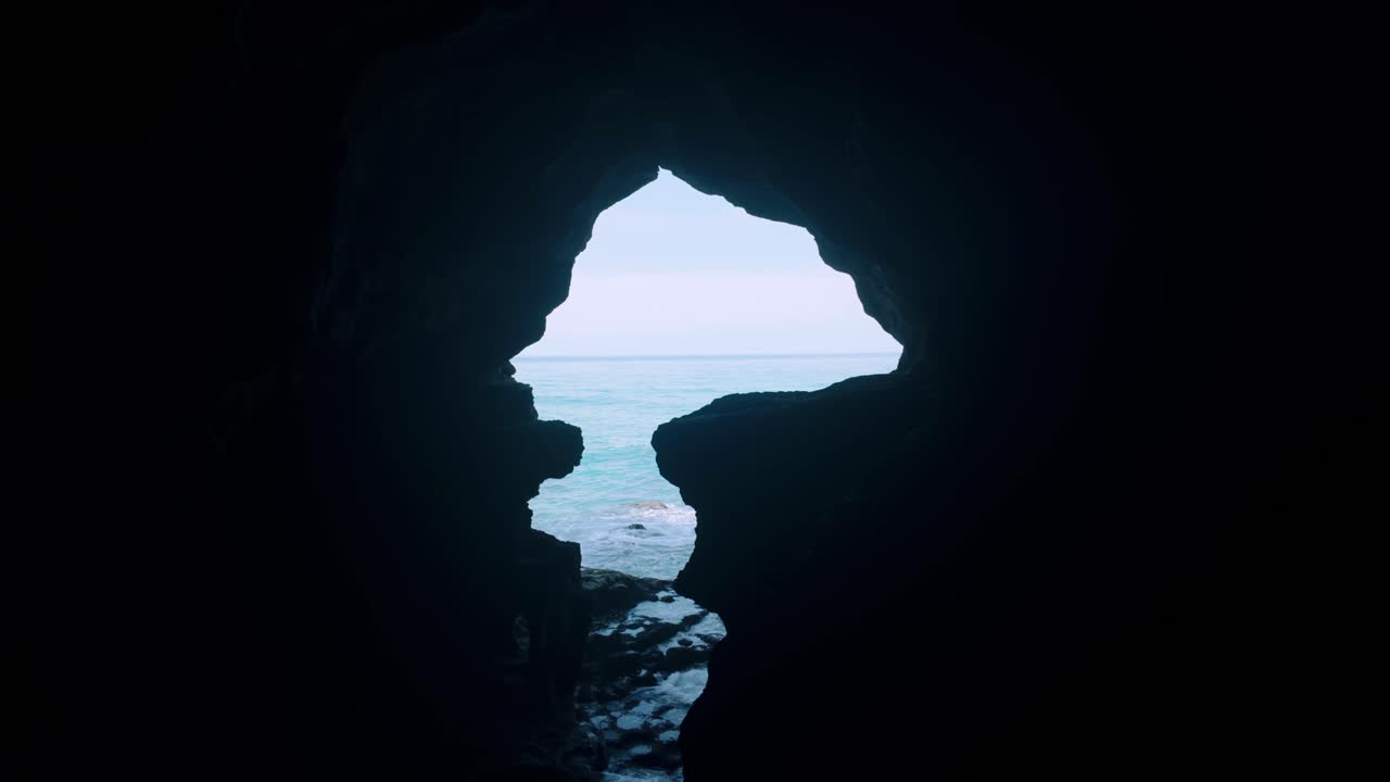 Sagoma dell'apertura di una grotta a forma d'Africa alle Grotte di Ercole, che si affaccia sull'oceano turchese.
