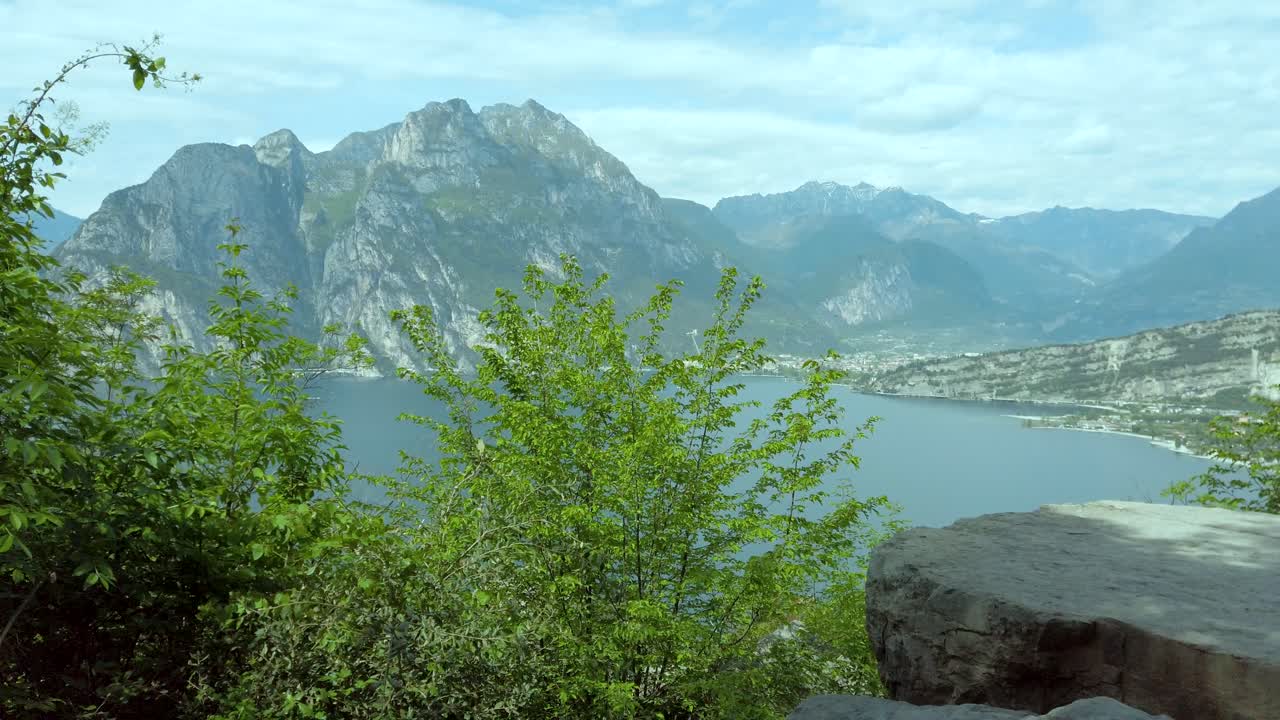 Parallakseudsigt fra klippeformationerne med udsigt over Gardasøen på en stormfuld dag i Nago Torbole, Italien.