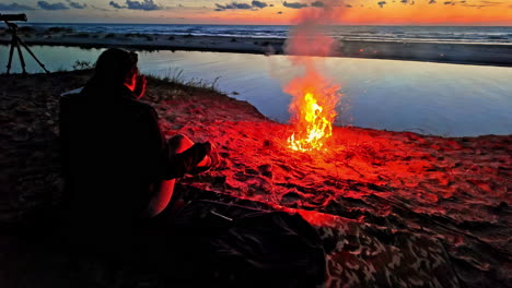 person enjoying a vibrant bonfire on a sandy beach at sunset
