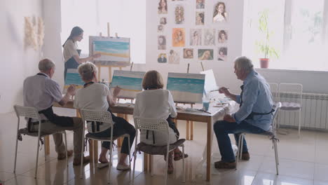 a group of old men and women friends watching together and repeating the painting technique behind the teacher