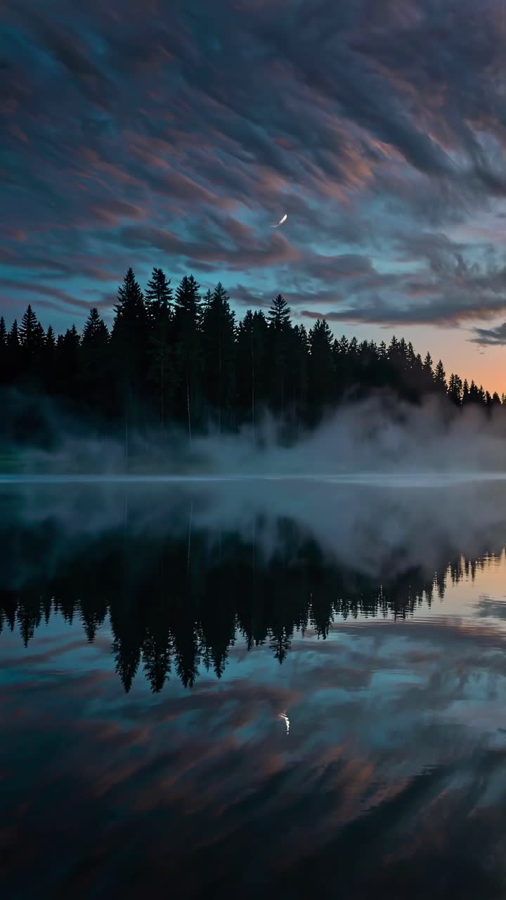 A serene landscape video with a low-angle view capturing a crescent moon, misty forest