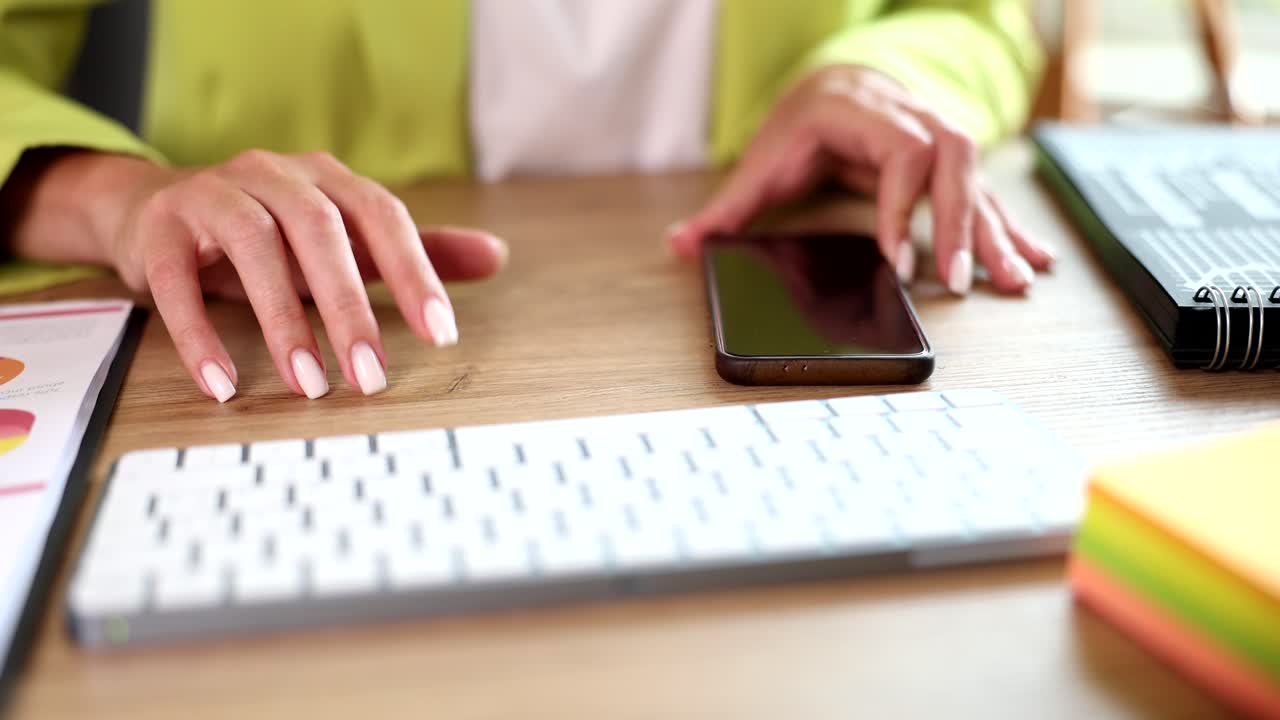 Office desk with woman's hands, keyboard, and phone