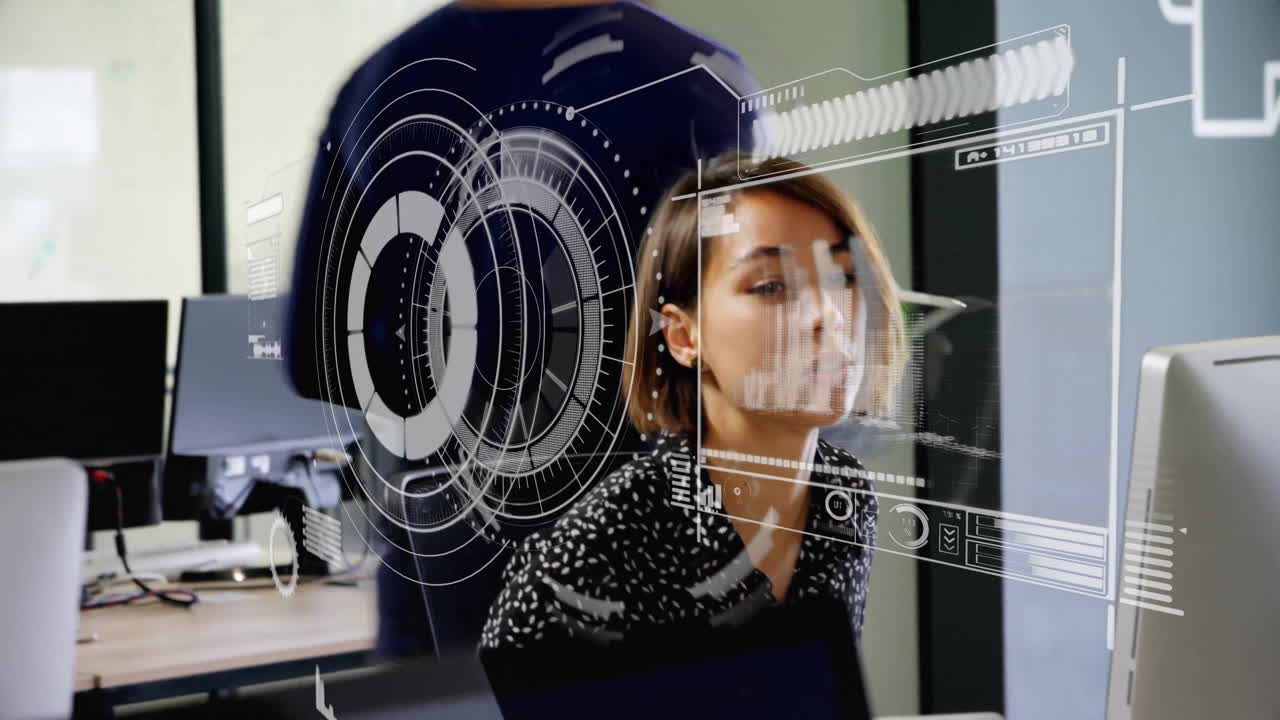 woman working on computer in tech office, colleagues exchanging tablet with AR interface graphics